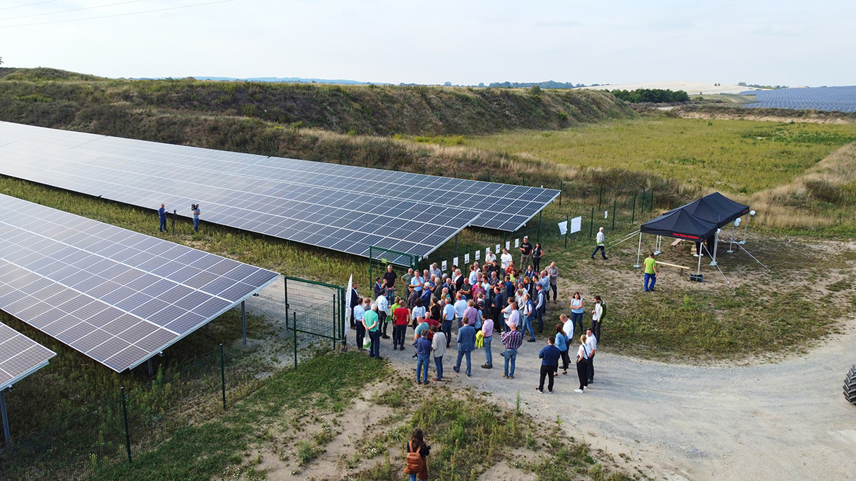 Solarpark Lüttow-Valluhn Eröffnungsfeier mit einer Gruppe Menschen am Eingang zum Solarpark.