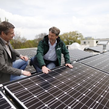 Zwei Männer vor den PV-Anlagen auf einem Dach im Domagkpark
